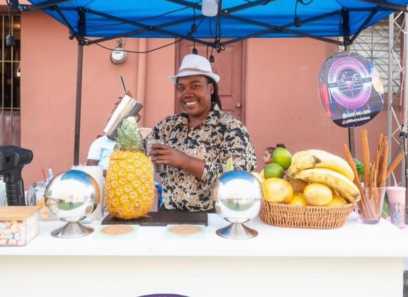 Emprendedora atendiendo un puesto de productos lácteos con mesa ordenada en la Feria de la Leche de Higüey.